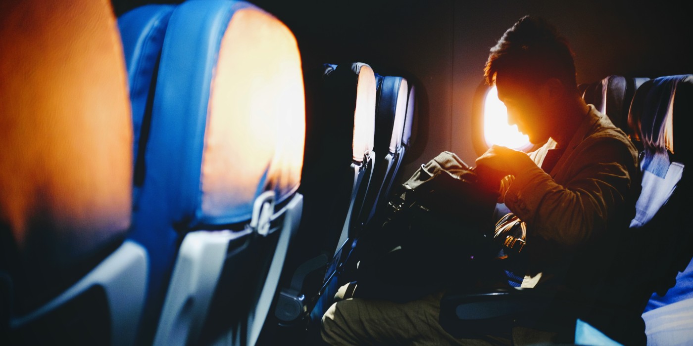 Person on a plane looks into their backpack.