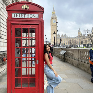 Cornell student leans against a red phone booth with Big Ben in the background.