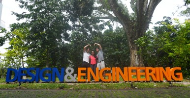 Global Intern Frank Fang makes a big heart with friends above a sign that reads "Design and Engineering."