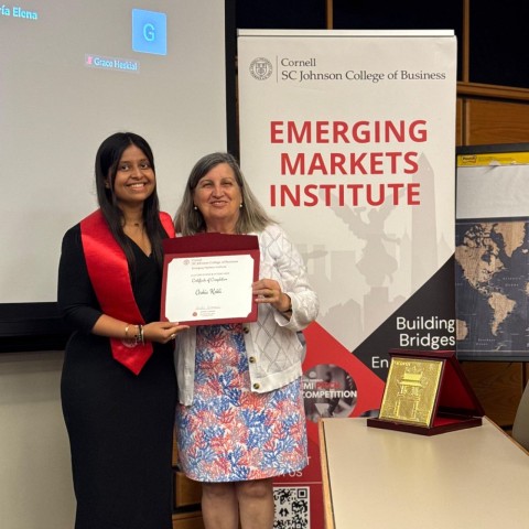 Ashoka student smiles for a photo with professor Lourdes Casanova, holding a certificate of completion. 