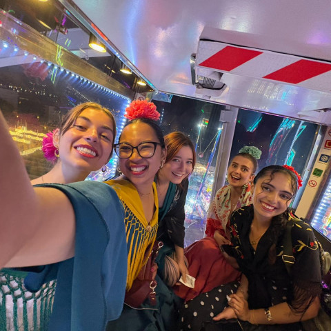 Cornell students pose for a selfie while taking public transit in Spain, wearing colorful outfits.